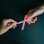 hands holding breast cancer pink paper ribbon